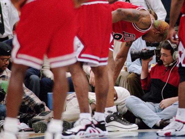 Chicago Bulls’ Dennis Rodman checks on courtside photographer Eugene Amos after he kicked him in groin during a game against the Minnesota Timberwolves.