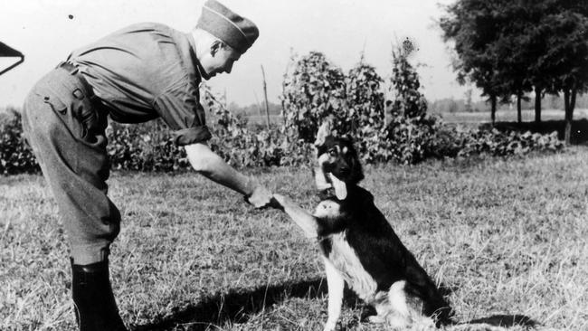 Caption SS officer Karl Hoecker shakes hands with his dog. Picture: United States Holocaust Memorial Museum