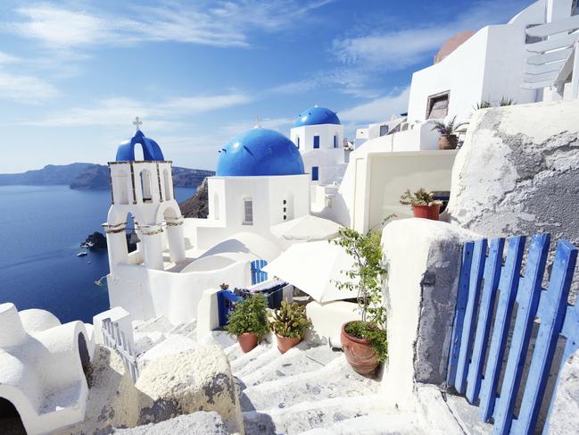 Bright morning scene of Oia Village is dominated by a blue gate and matching church domes.Picture: iStockDoc Holiday, Escape