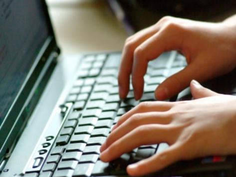 Hands typing on laptop keyboard.