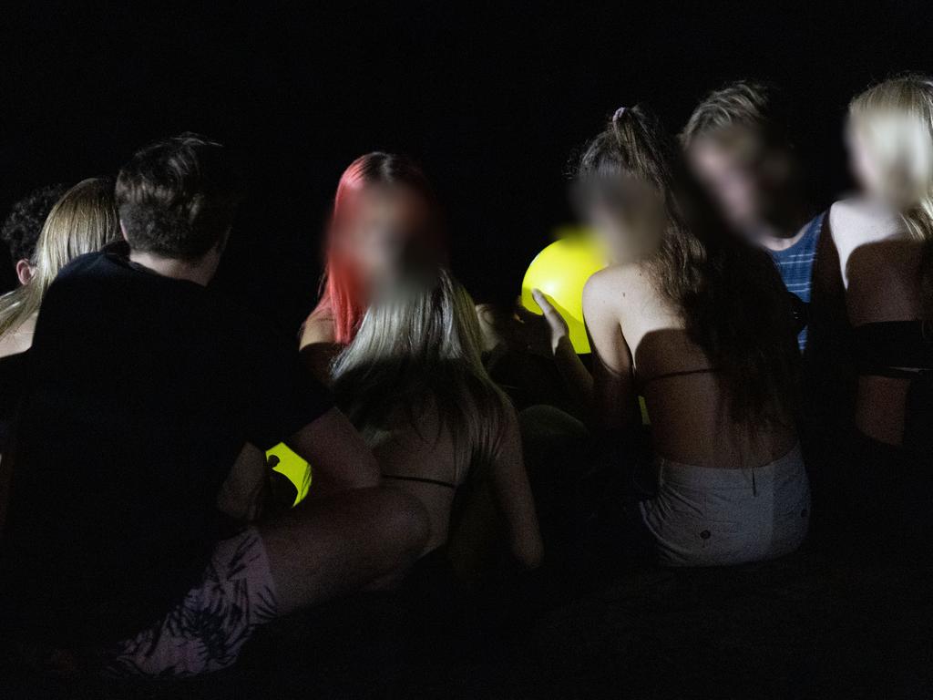 A group of kids inhale nitrous oxide – dispensed from a cream charger into a yellow balloon.