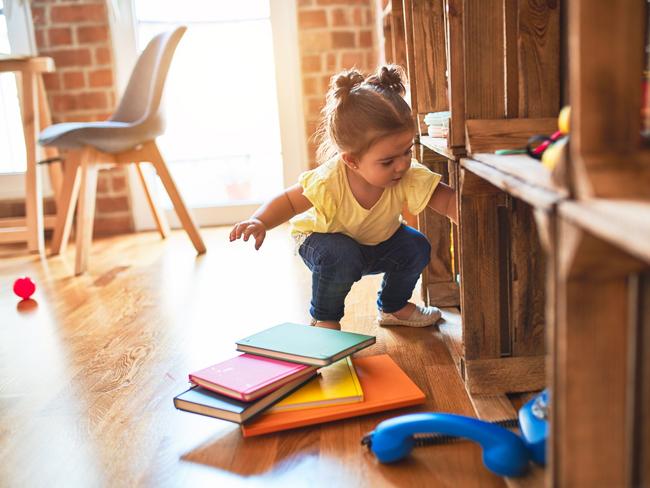 Beautiful toddler taking books of shelving at kindergarten