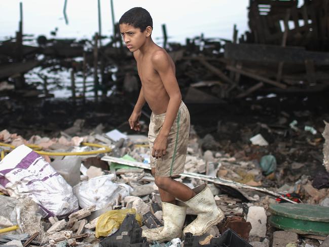 RIO DE JANEIRO, BRAZIL - JULY 29: A boy looks for items to recycle along the polluted Cunha canal which flows into the notoriously polluted Guanabara Bay, site of sailing events for the Rio 2016 Olympic Games, on July 29, 2015 in Rio de Janeiro, Brazil. The Rio government promised to clean 80 percent of pollution and waste from the bay in time for the games but admits that goal now is unlikely to be reached. August 5 marks the one-year mark to the start of the Rio 2016 Olympic Games. (Photo by Mario Tama/Getty Images)