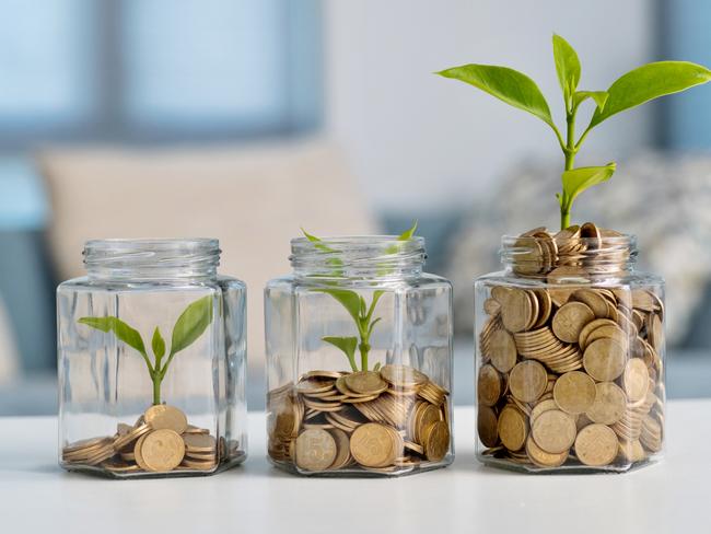 Green plant growing in glass jar with coins, superannuation generic