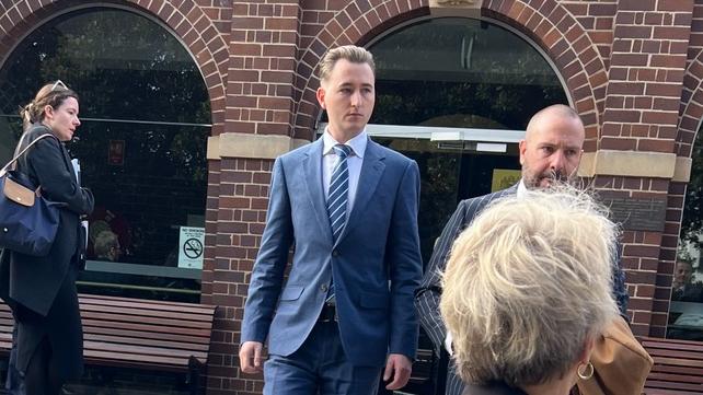 Former NSW police officer Matthew Cameron (blue suit) emerges from Manly Local Court on Monday.