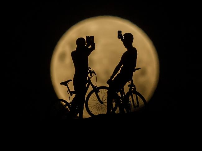 PERTH, AUSTRALIA - JANUARY 31:  Photo Illustration showing people with bicycles taking photos of the Super moon on January 31, 2018 in Lancelin, Australia. Last seen from Australia in December 1983, a Super Blue Blood Moon is the result of three lunar phenomena happening all at once. Not only is it the second full moon in January, but the moon will also be close to its nearest point to Earth on its orbit, and be totally eclipsed by the Earth's shadow.  (Photo by Paul Kane/Getty Images)