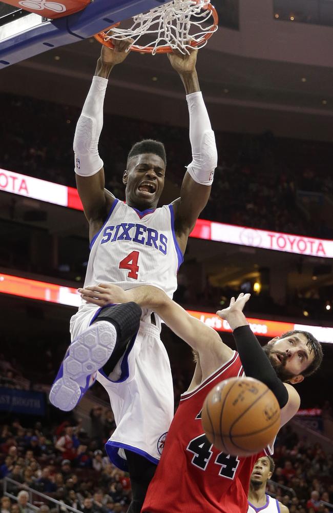 Philadelphia 76ers' Nerlens Noel hangs on the rim after a dunk against Chicago Bulls' Nikola Mirotic.