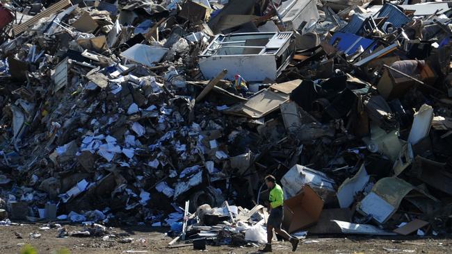 A Brisbane City Council worker is dwarfed by a mountain of houshold debris dumped next to the sports grounds at the Victoria Park Golf Club following devastating floods in Brisbane, Monday, Jan. 17, 2011.