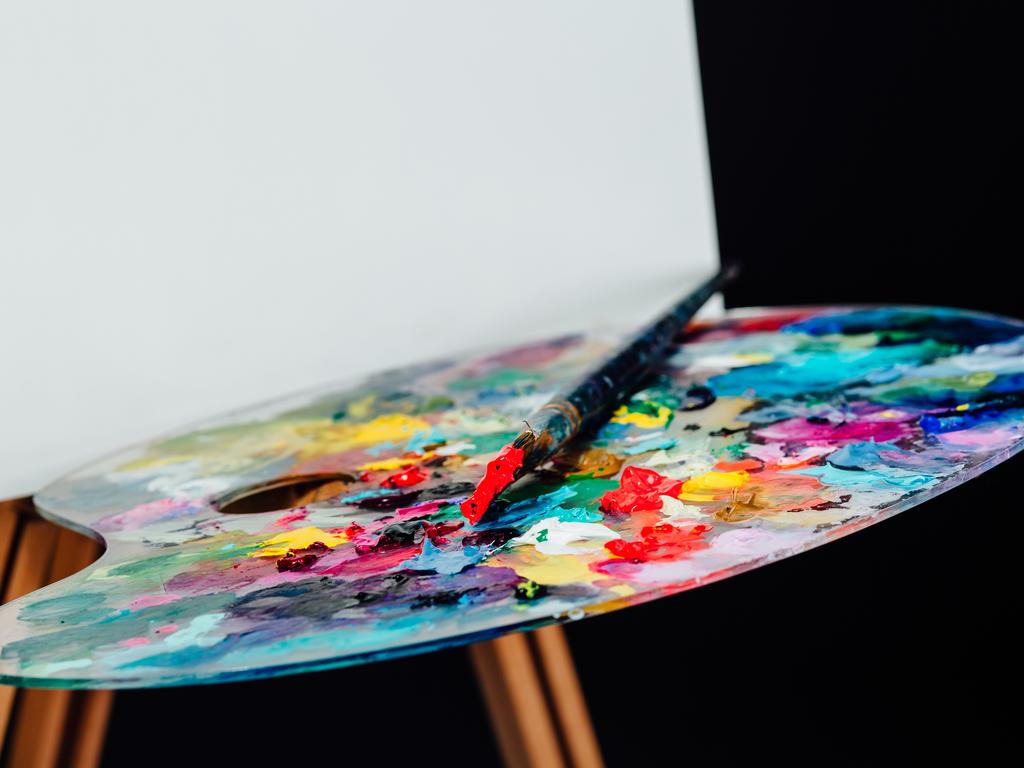 Tools of the artist. Brushes, wooden easel tripod, palette colorful. Black background, studio Nobody, close-up