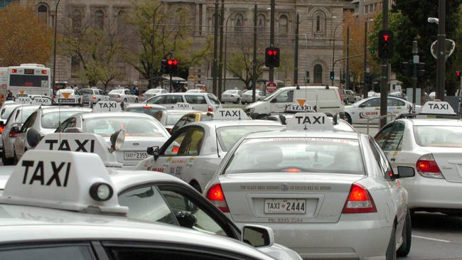 Taxi drivers leaving to drive through the city after protesting outside the District court Samuel Way building in Adelaide.