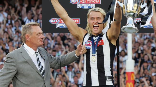 Collingwoods Darcy Moore and Craig Mcrae hold aloft the premiership cup after defeating the Brisbane Lions by 4 points at the MCG. Picture Lachie Millard