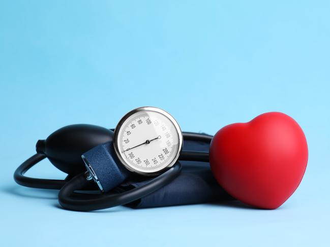 Blood pressure meter and toy heart on light blue background