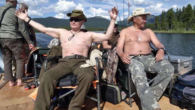 Vladimir Putin, left, accompanied by defence minister Sergei Shoigu, gestures as he fishes in the remote Tuva region in southern Siberi in 2017. Picture: AFP/SPUTNIK