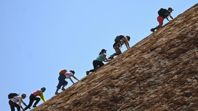 Tourists are seen climbing Uluru, also known as Ayers Rock at Uluru-Kata Tjuta National Park in the Northern Territory, Friday, October 25, 2019. Today is the last day people will be able to climb Uluru. (AAP Image/Lukas Coch) NO ARCHIVING