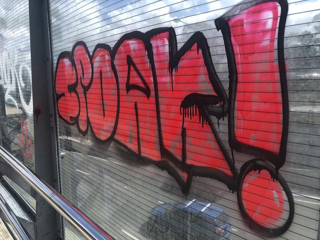 Graffiti  on a glass panel above the multi-lane roadway at the intersection of Warringah Rd and Forest Way at Frenchs Forest on September 20, 2022. Graffiti vandalism has not been cleaned away from the location despite repeated requests to the NSW Government that go back 12 months. Picture: Jim O'Rourke