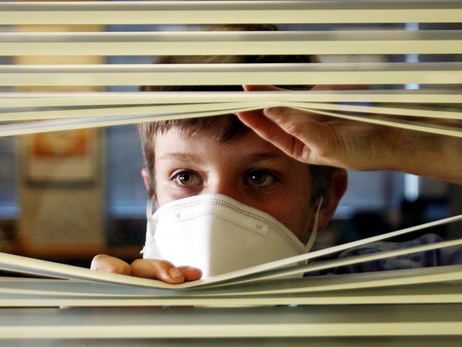 Young boys wearing face masks and peering out the window