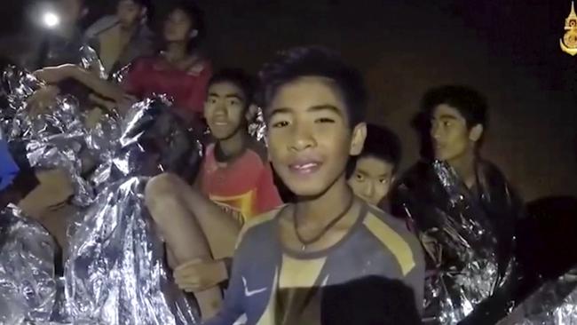 The boys smile as a Thai Navy SEAL medic tends to them inside the cave in Mae Sai, northern Thailand. Picture: Royal Thai Navy Facebook Page via AP.