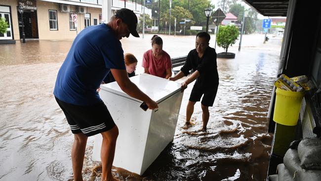 LAIDLEY, AUSTRALIA – MAY 13: Locals help a Chinese restaurant owner (R) as he tries to salvage a freezer as floodwater inundate his business on May 13, 2022 in Laidley, Australia. Parts of southeast Queensland are on flood watch as the state continues to experience heavy rainfall. (Photo by Dan Peled/Getty Images)