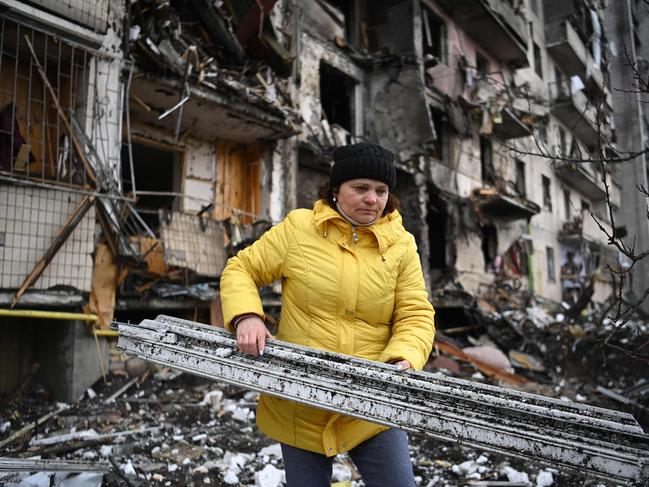 A woman clears debris at a damaged residential building after a Russian shell hit it. Picture: Getty