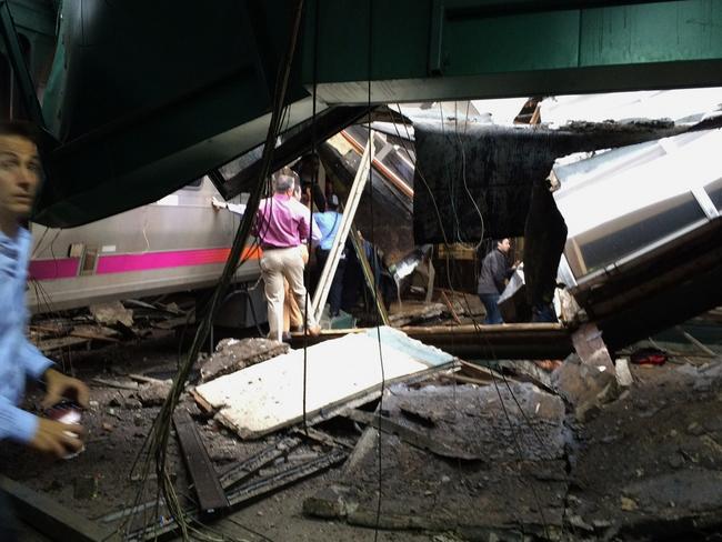 People examine the wreckage of a New Jersey Transit commuter train that crashed into the train station. Picture:William Sun via AP