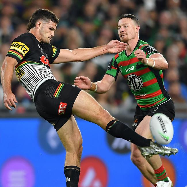 Damien Cook closes in on Nathan Cleary as he launches a kick.