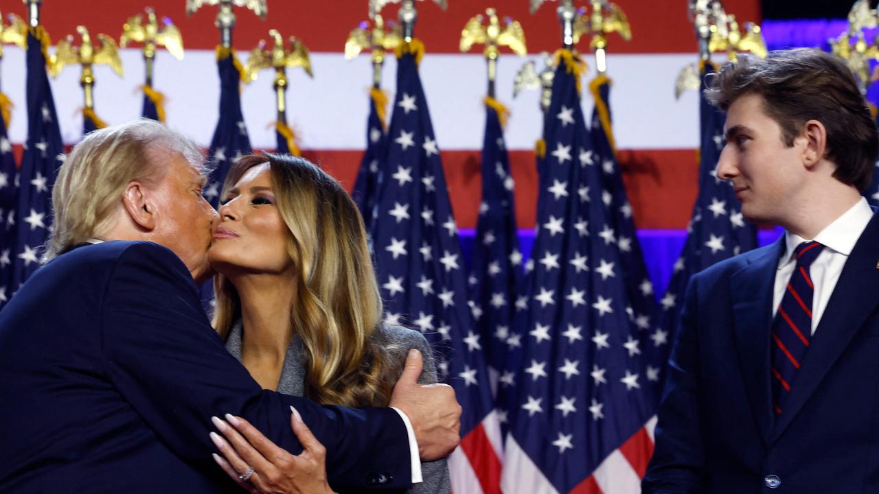 Republican presidential nominee, former U.S. President Donald Trump kisses former first lady Melania Trump as their son Barron Trump (R) looks on.