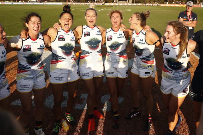 Crows players sing the team song after beating the Melbourne Demons.