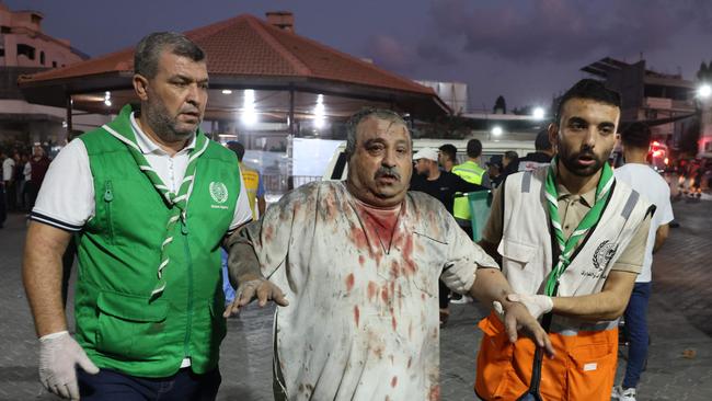 Emergency personnel help an injured Palestinian man into Al-Shifa hospital in Gaza City following an Israeli air strike. Photo by MOHAMMED ABED / AFP