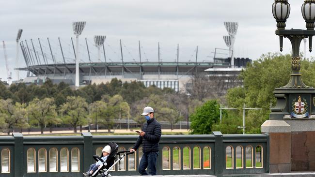 A man walks across Princes Bridge with the empty MCG in background during Melbourne’s lockdown. Picture: NCA NewsWire / Andrew Henshaw