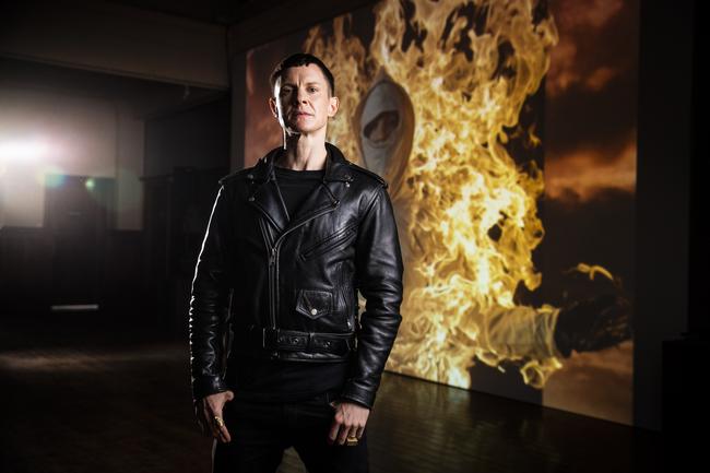 Artist Cassils in front of a large projection of their performance Inextinguishable Fire, a video of him doing an epic fire stunt which can be seen as part of A Forest. Picture: RICHARD JUPE