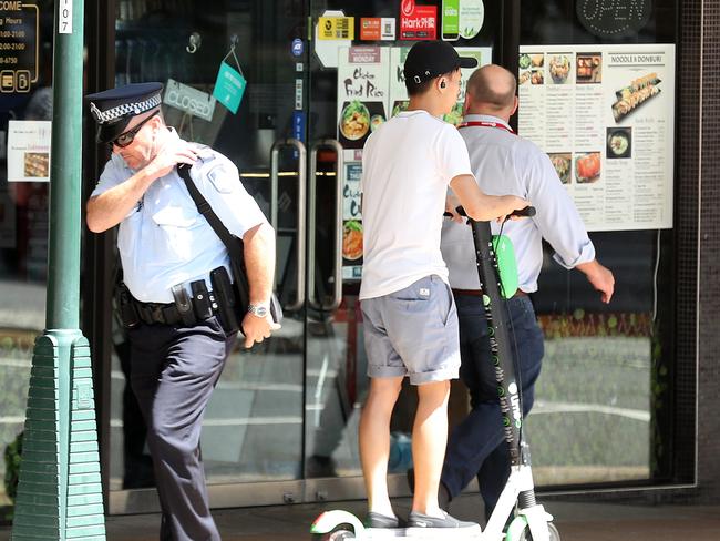 File photo: Lime scooter rider passes a policeman on the footpath, Brisbane. Picture: Liam Kidston.