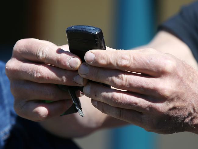 Tony Lockett holds his pre-2000 Nokia flip phone as he talks with Robbo. Picture: Michael Klein