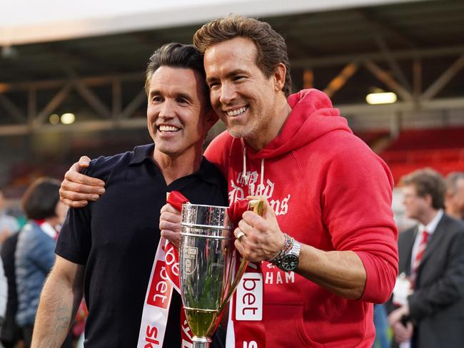 WREXHAM, WALES - APRIL 26: Rob McElhenney and Ryan Reynolds, co-owners of Wrexham AFC, pose for a photo with the trophy following the club's promotion to the Sky Bet Championship during the Sky Bet League One match between Wrexham AFC and Charlton Athletic FC at Racecourse Ground on April 26, 2025 in Wrexham, Wales. (Photo by Kya Banasko/Getty Images)