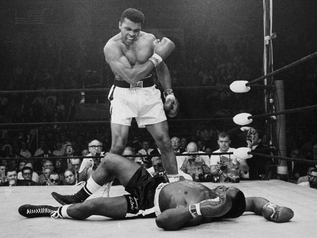 Now named Muhammad Ali, the heavyweight champ, stands over Sonny Liston after knocking him with a short hard right to the jaw, in a 1965 rematch.