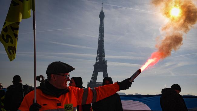 A members of the SUD labour union holds a flare during a demonstration on the Parvis du Trocadero, across the Seine river from the Eiffel Tower, during a cross-sector labour union protest against France's controversial pension reform bill, in Paris, on February 9, 2023. - The planned reforms include hiking the retirement age from 62 to 64 and increasing the number of years people must make contributions for a full pension. (Photo by Alain JOCARD / AFP)