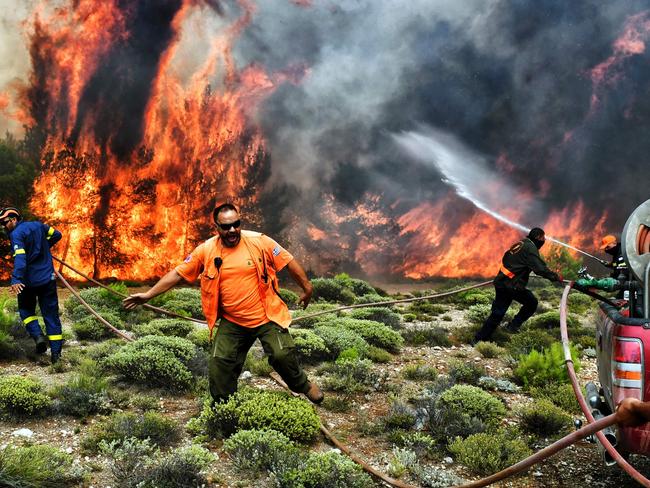 Firefighters and volunteers try to extinguish flames during a wildfire at the village of Kineta, near Athens, on July 24, 2018. Picture: AFP