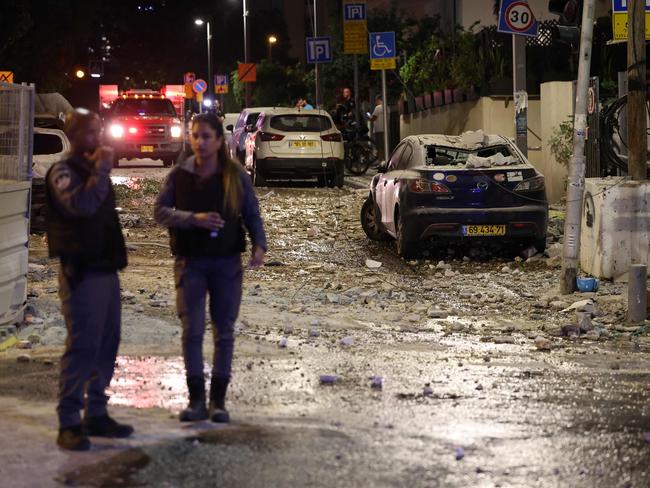 Israeli security forces stand along a debris-strewn street in Tel Aviv, after it was hit by a rocket fired by Palestinian militants from the Gaza Strip on October 7, 2023. Picture: AFP/ Jack Guez