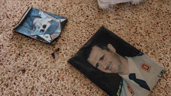 Portraits of toppled Syrian president Bashar al-Assad lie on the ground at an army barracks in the town of Dummar near Damascus. Picture: AFP.