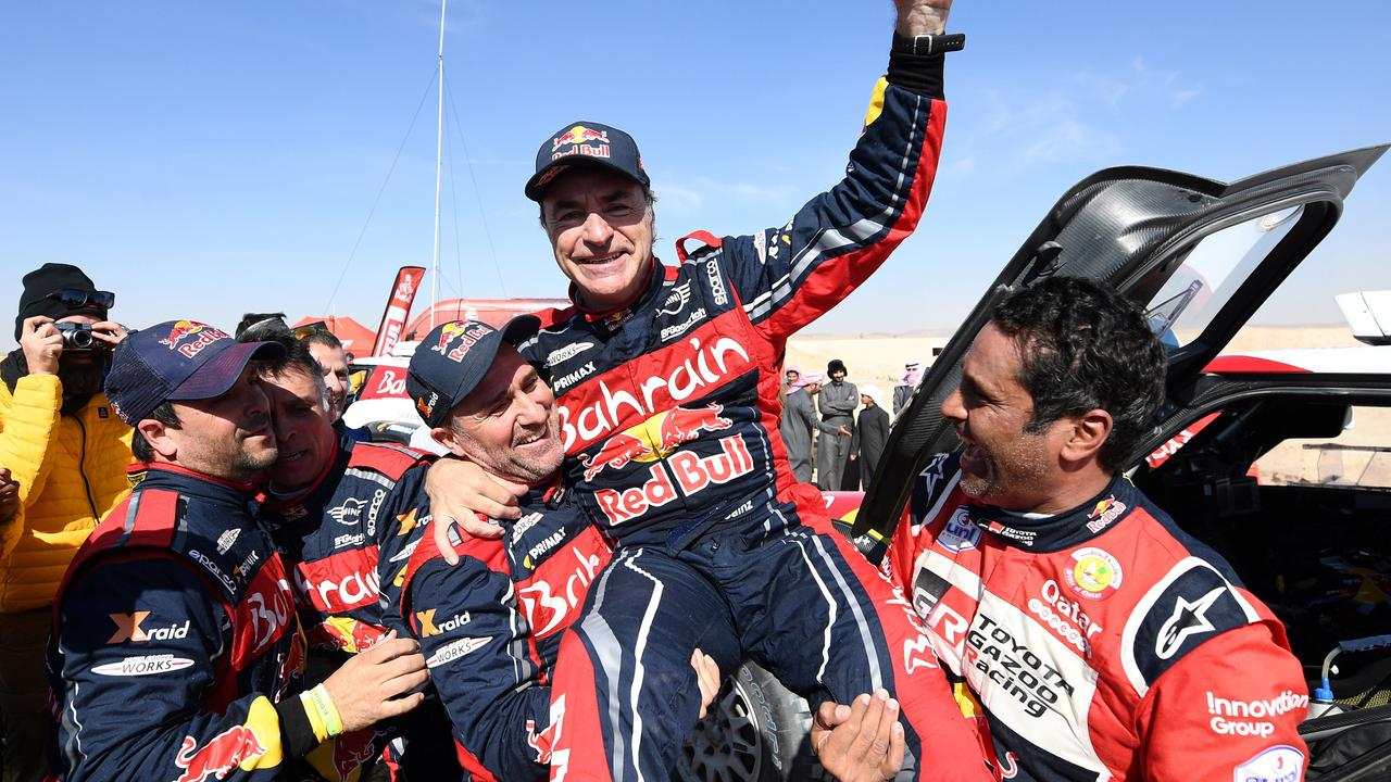 Carlos Sainz is congratulated by second-placed Nasser Al-Attiyah (R) and third-placed Stephane Peterhansel at the end of stage 12. (Photo by FRANCK FIFE / AFP)