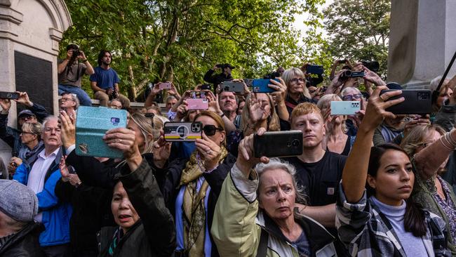 Members of the public watch the cortege carrying the coffin of Queen Elizabeth II from Buckingham Palace to Westminster Hall.