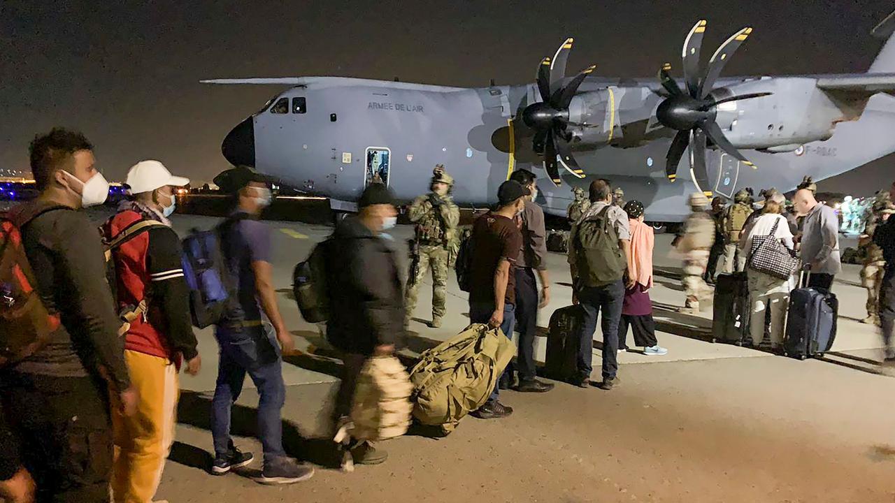 French and Afghan nationals line up to board a French military transport plane at the Kabul airport.