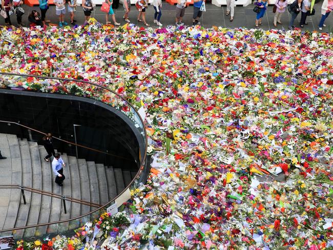 The floral tribute at Martin Place continues to expand, with members of the public pouring into the area to lay flowers as a mark of respect for those killed and were involved in the siege on Monday. An office workers walk down a set of stairs the leads underneath Martin Place. Picture: Toby Zerna