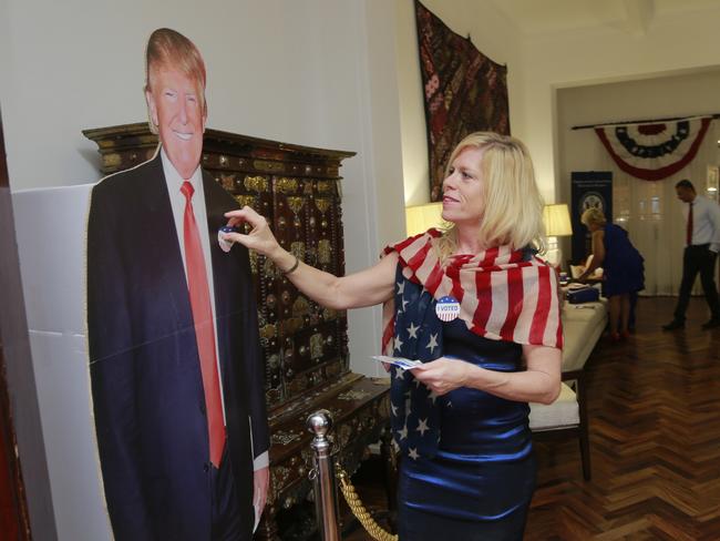 An American citizen pastes a sticker on a cardboard cut out photograph of US presidential candidate Donald Trump at the US deputy ambassador's residence in Colombo, Sri Lanka, Wednesday, Nov. 9, 2016. (AP Photo/Eranga Jayawardena)