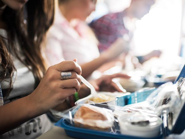 Unrecognizable people eating lunch while traveling by airplane.