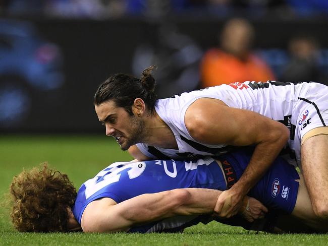 Brodie Grundy of the Magpies (right) tackles Ben Brown of the Kangaroos (left).