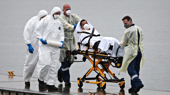 A Ruby Princess staff member being evacuated from the virus-stricken cruise ship while surrounded by police and medical staff. Picture: Adam Yip