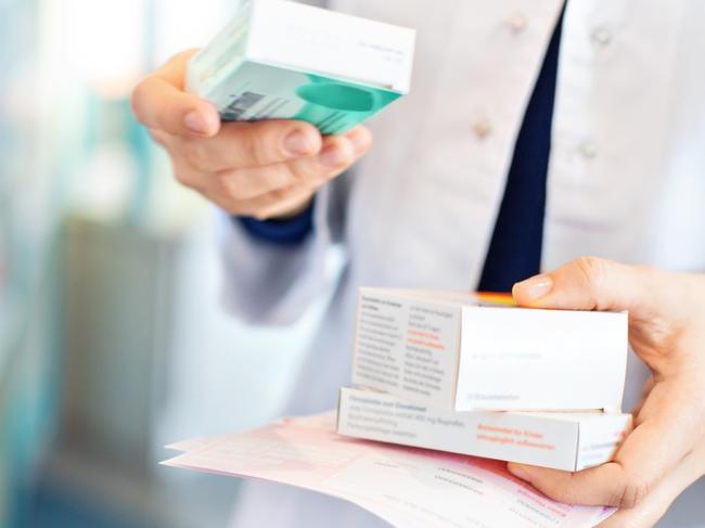 Closeup of pharmacist's hands taking medicines from shelf at the pharmacy