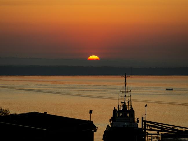 The rising morning sun peeking over the thick haze looking over the Darwin Harbour on Tuesday. Picture: Floss Adams.