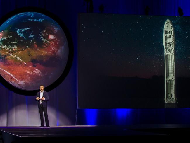 Elon Musk makes a presentation with the image of a terraformed Mars and a cutaway of his Starship design behind him. Picture: AFP