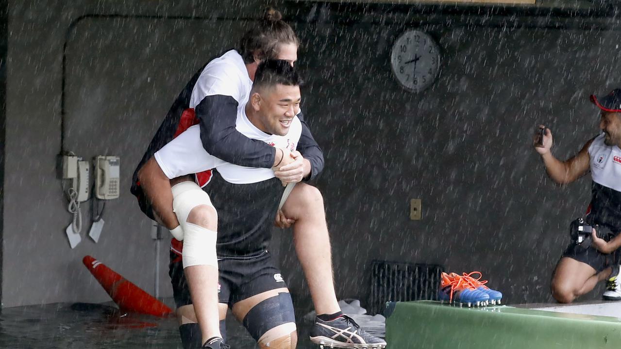 Japan player Jiwon Koo carries teammate James Moore in a flooded walkway.